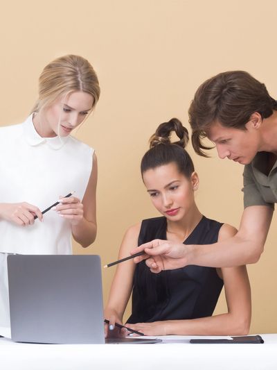Three professionals collaborating around a laptop in a workspace.