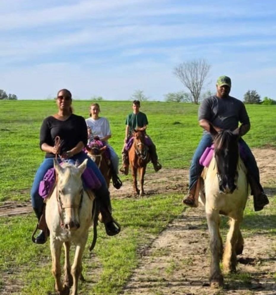 Family group riding horses together on open Texas ranch trails at Chisholm Trail Rides.