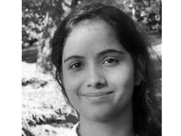 Black and white portrait of a smiling woman outdoors.