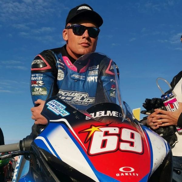 Motorcycle racer posing with bike number 69.