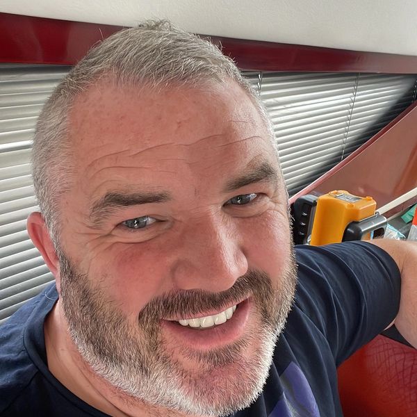 Smiling man with gray hair and beard indoors.