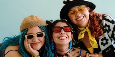 Three vibrant young neurodiverse people smiling