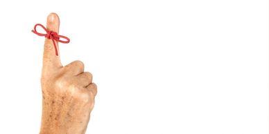 older person's hand with a piece of red string tied as a reminder