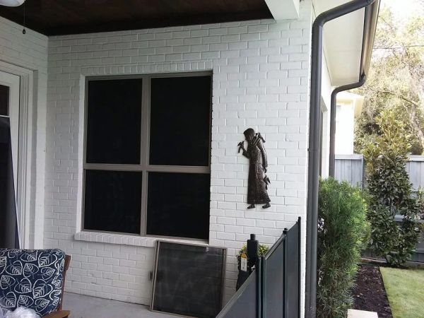 A white brick wall with a decorative figure and a large window.