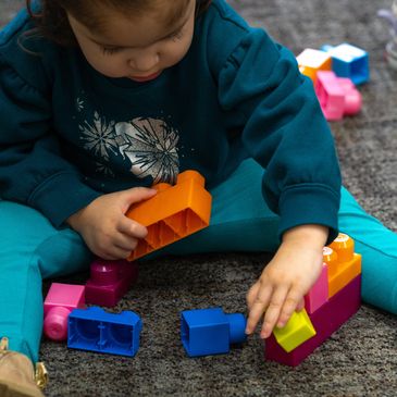Latina toddler plays with blocks in a safe and stimulating learning environment Wee Care STEM