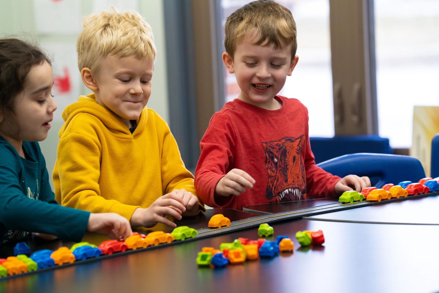 group of children smiling and playing with toy counting cars. stimulating school environment Wee Car