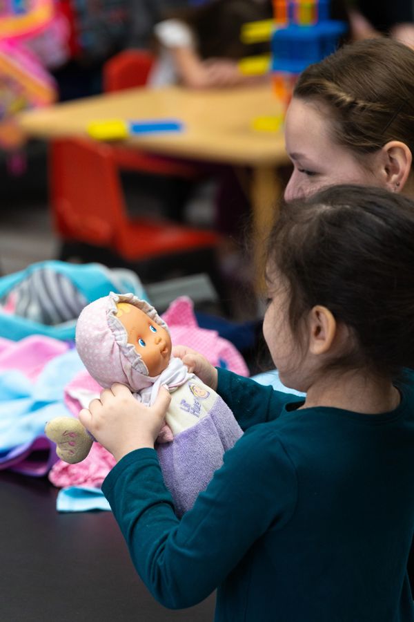 Latina student plays with doll developing imagination and making friends in a safe and stimulating