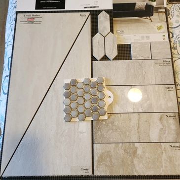 Tile samples in various shades of ivory, silver, and natural colors with a hexagonal mosaic piece.