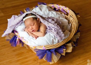Newborn baby peacefully sleeping in a decorated basket.