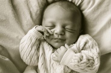 Peaceful newborn baby sleeping in a cozy sweater.