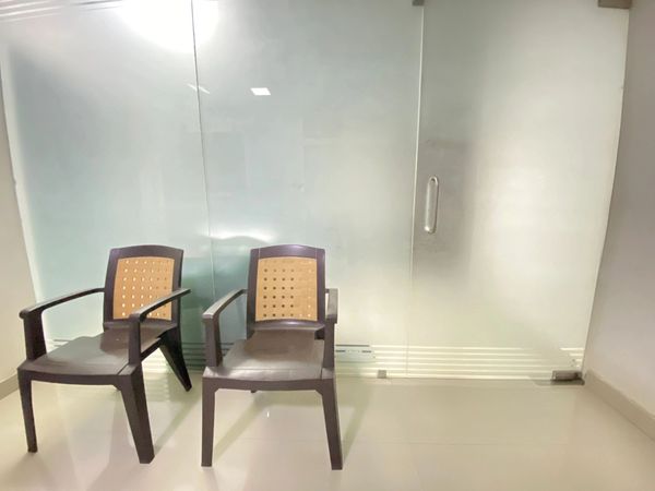 Two plastic chairs near a glass door in a bright room.