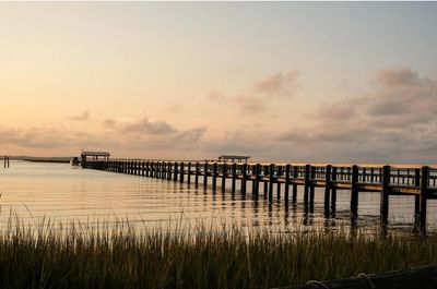 A long wooden pier extending over calm water at sunset.