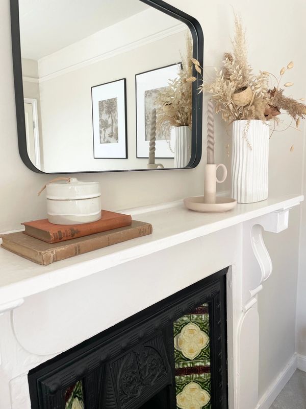 Minimalist mantel decor with dried flowers, vintage books, and a twisted candle.