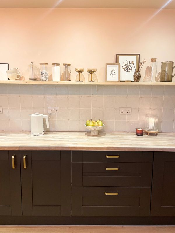Minimalist kitchen counter with dark cabinets, pears, candles, and decorative jars.