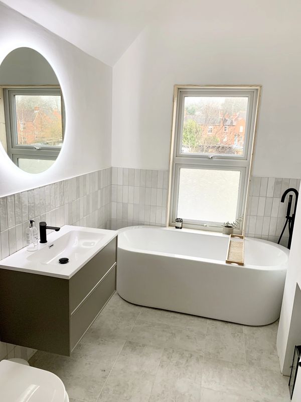 Modern white bathroom with a sleek bathtub and floating vanity.
