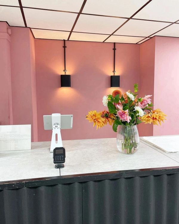 A reception desk with flowers and soft pink walls under warm lighting.