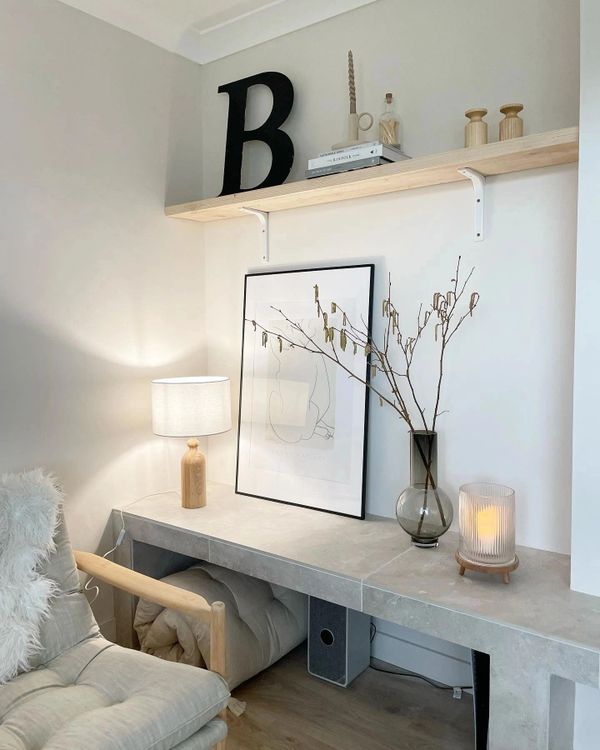 Cozy modern corner with a soft chair, minimalistic artwork, and warm lighting.