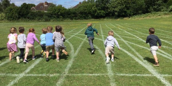 Children racing on a grass track outdoors.