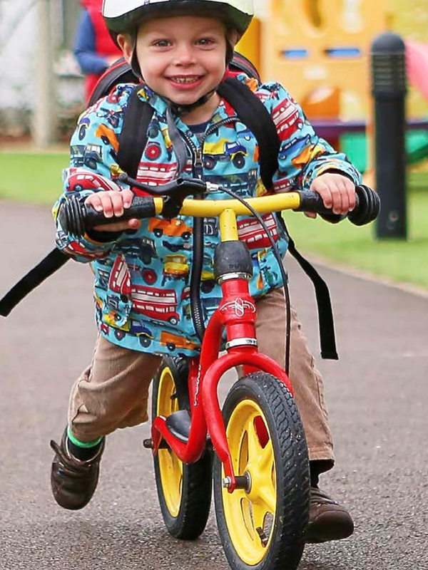 Happy child riding a red balance bike.