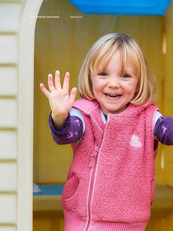 Smiling child with outstretched hand in pink vest.