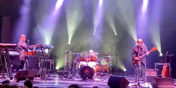 Band performing live on stage with vibrant lighting effects.