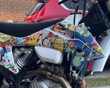 Motorcycle decorated with colorful cartoon character stickers including Pikachu and Stitch.