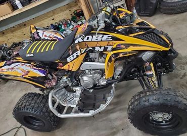 Yellow and black Yamaha quad bike with custom graphics and rugged tires.