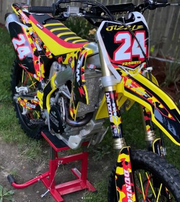 Yellow and black Suzuki dirt bike with number 24 on display stand.