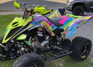 Brightly colored Yamaha quad bike with bold patterns and decals.