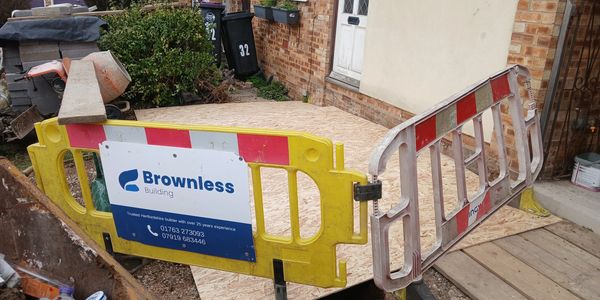 Temporary barriers and plywood board at a building entrance under construction.