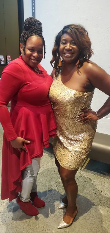 Two women posing for photo in red and gold dresses