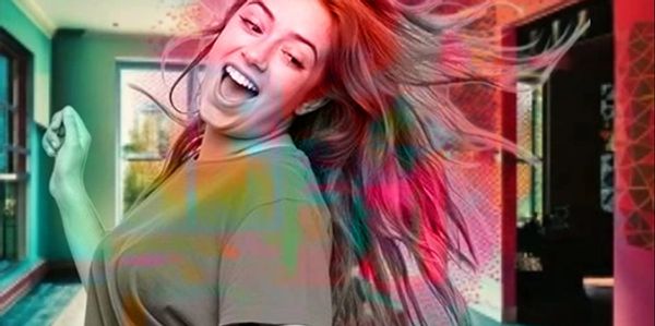 Joyful woman dancing with colorful hair effects in a vibrant room.