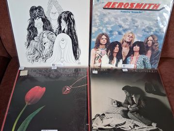 Four classic rock vinyl albums displayed on a table.