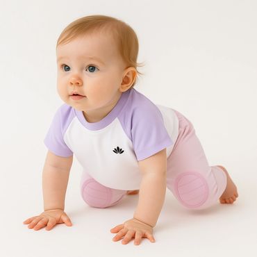 Adorable baby crawling, wearing a white and lavender shirt with pink pants.
