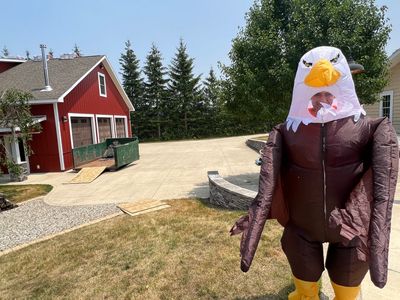 Person in an inflatable eagle costume standing outside.