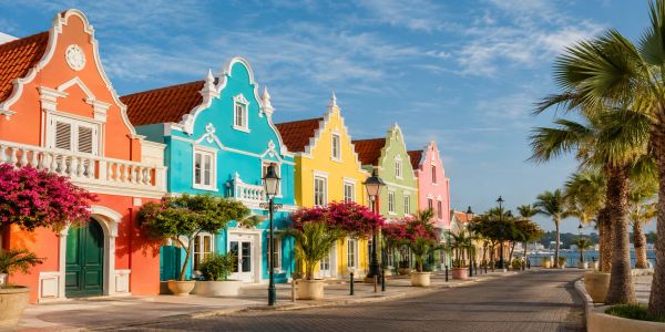 Colorful colonial-style houses by the waterfront under a blue sky.