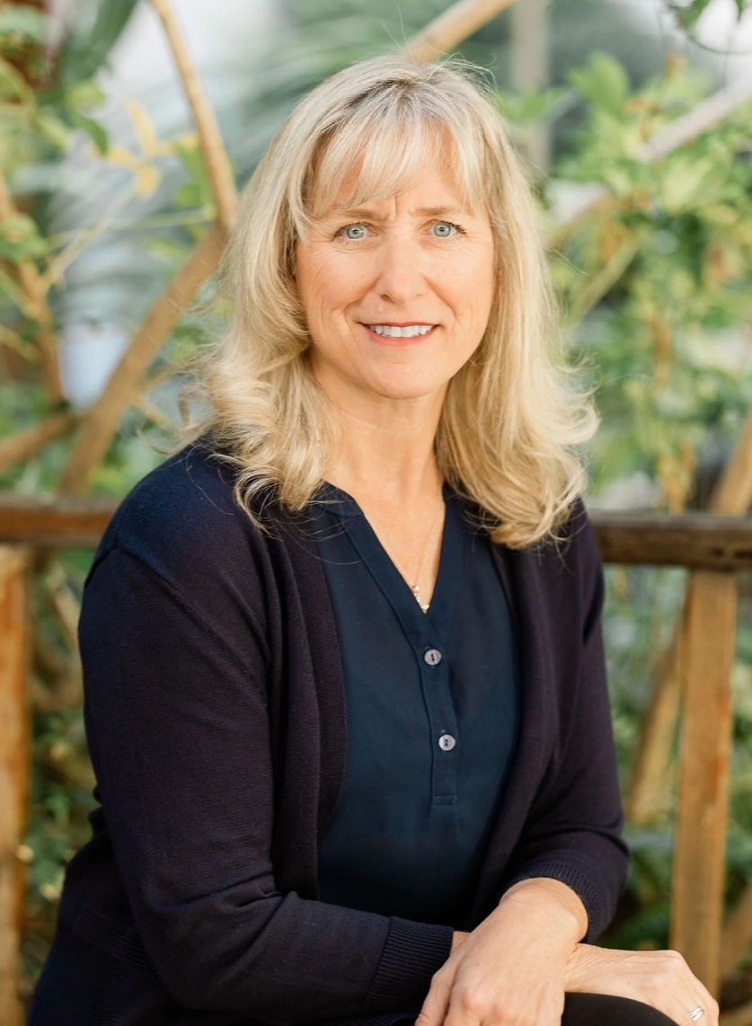 IBCLC and founder Leilani Songer sits in a garden. Professional headshot.