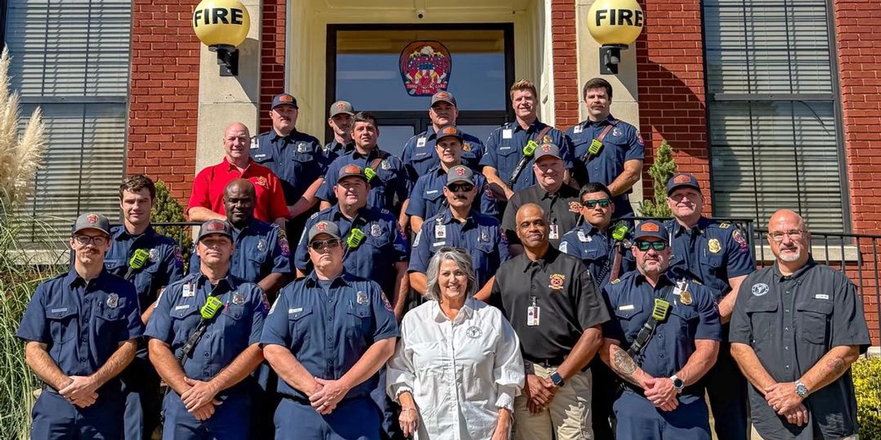Group photo of firefighters and staff outside a fire station.