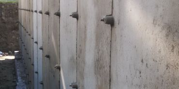 Close-up of a concrete wall with bolts and natural surroundings.