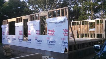 Early stage of house construction with wooden framing and Tyvek HomeWrap.