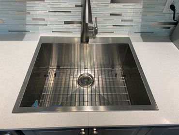 Modern stainless steel kitchen sink with a sleek faucet and tiled backsplash. Home Improvements Delray Beach
