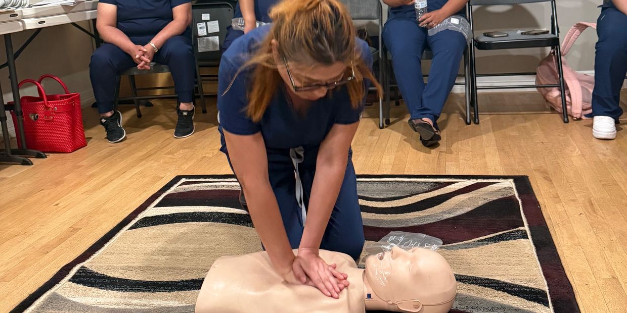 Woman practicing CPR on a training mannequin during a class.