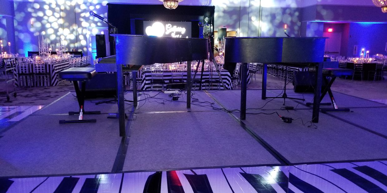 Stage with two grand pianos and festive lighting.