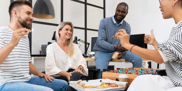 Colleagues enjoying pizza and foosball during a break at the office.