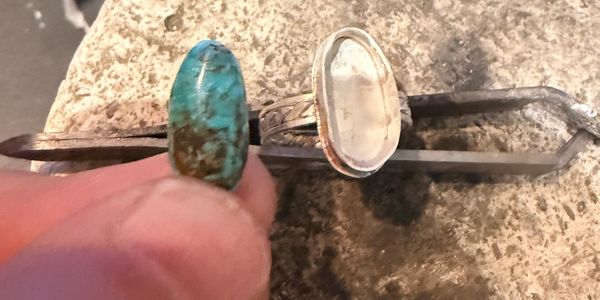 Turquoise stone and ring setting on a workbench.