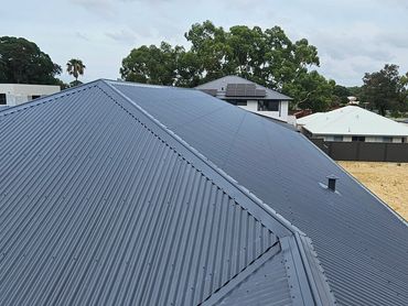 Metal roof with a modern design under a cloudy sky.