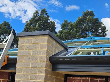Close-up of a building corner under construction with a blue sky.