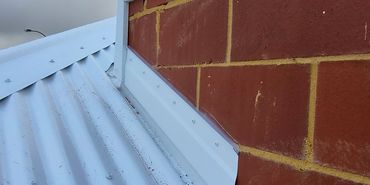Close-up of brick wall and white corrugated metal roof.