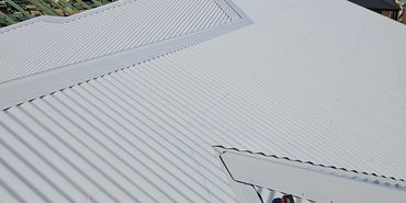 Newly installed white metal roof under clear sky.