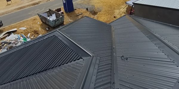 A newly installed black metal roof on a building under construction.